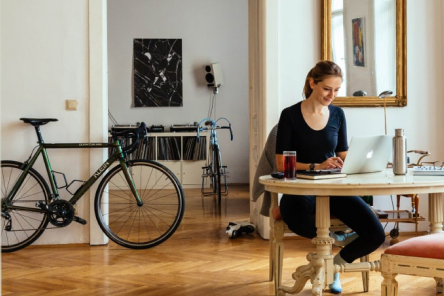 Persoon aan bureau met fiets in de kamer